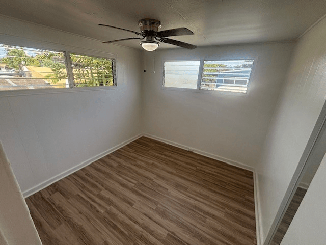 A room with a ceiling fan and wooden flooring.